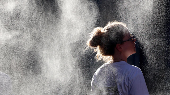 A woman cools off under a mist sprayer during a heatwave in Bordeaux, southwestern France on June 21, 2026