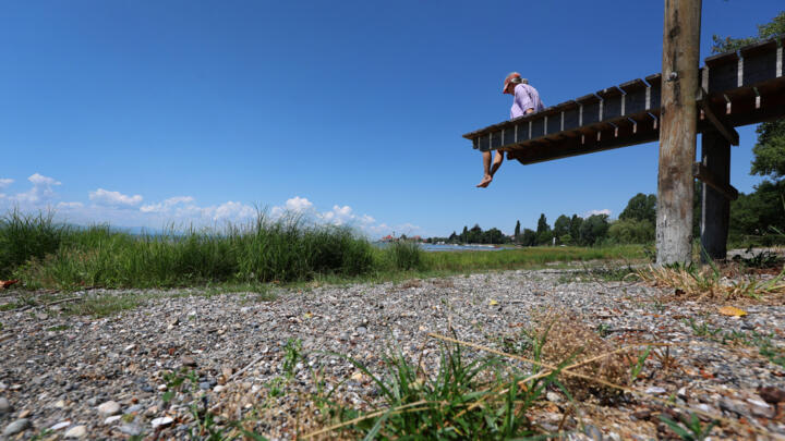 A woman lies on a jetty that ends at the dry shore of Lake Constance in Wasserburg, southern Germany, on July 2, 2026.