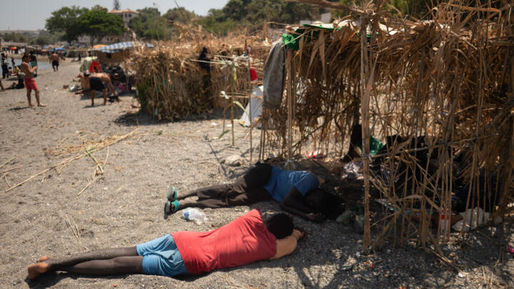Migrants rest next to makeshift shelters in Ceuta on August 15, 2026. 
