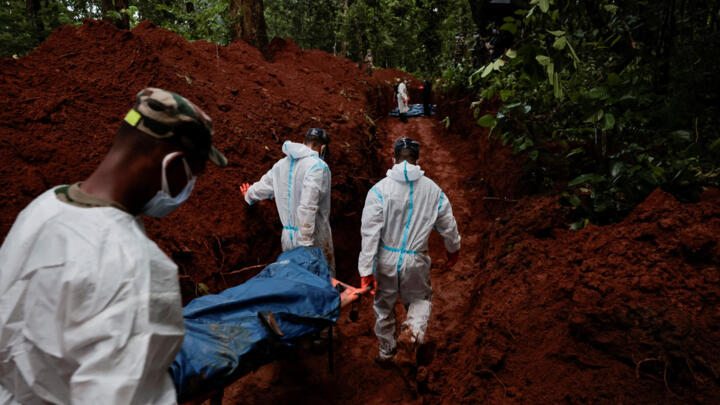 Agentes de la Fuerza de Policía Armada (APF) trabajan en el traslado de cuerpos hacia una fosa en el sitio de entierro masivo de Devghat para las víctimas de las mortales inundaciones repentinas y deslizamientos de tierra en Chitwan, Nepal, el 30 de agosto de 2026.