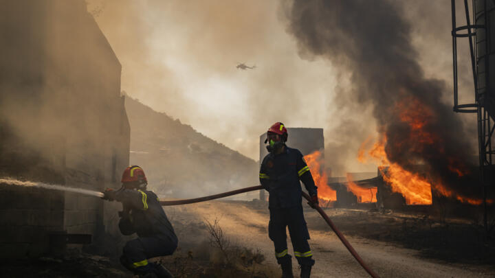 Firemen work to extinguish a blaze that broke out at a livestock facility near Kouvaras, south of Athens, on August 10, 2026