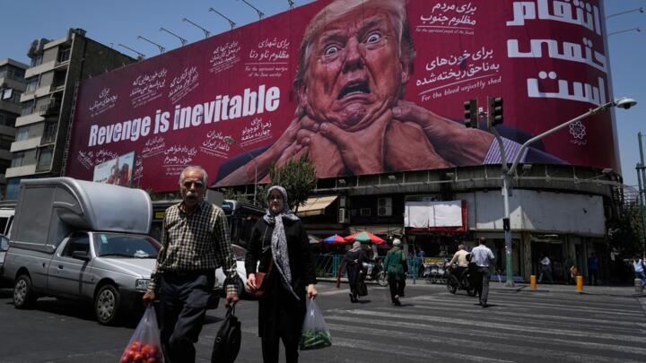 Pedestrians walk past a billboard depicting US President Donald Trump being grabbed by the neck in Tehran on July 27, 2026.