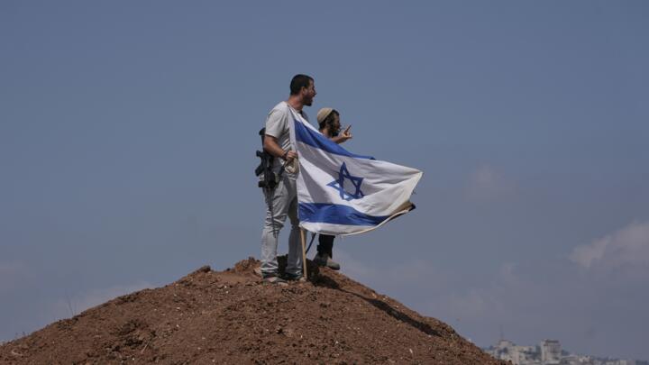 Israeli settlers put up an Israeli flag on a hilltop on the outskirts of the West Bank city of Beit Sahour on August 14, 2026