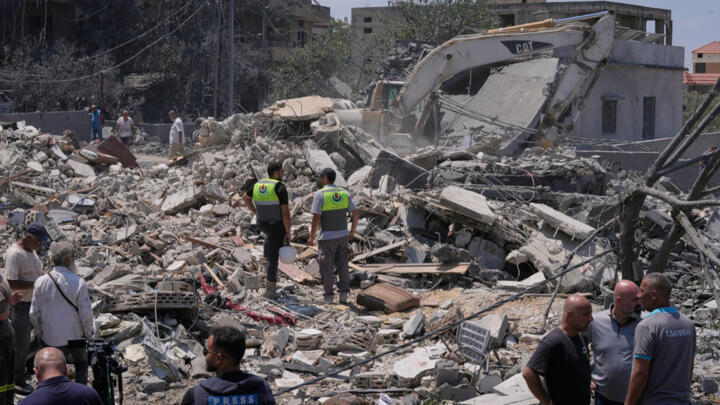 People and rescue workers gather on a destroyed house that was hit by an Israeli airstrike in Deir al-Zahrani village, southern Lebanon on August 15, 2026.