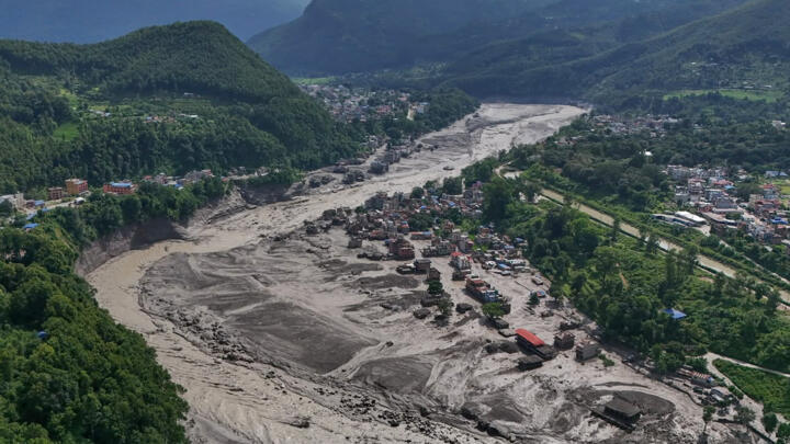 Damaged houses stand precariously near the swollen, debris-choked banks of the Trishuli River after flash floods in Nepal's Nuwakot district on August 26, 2026.