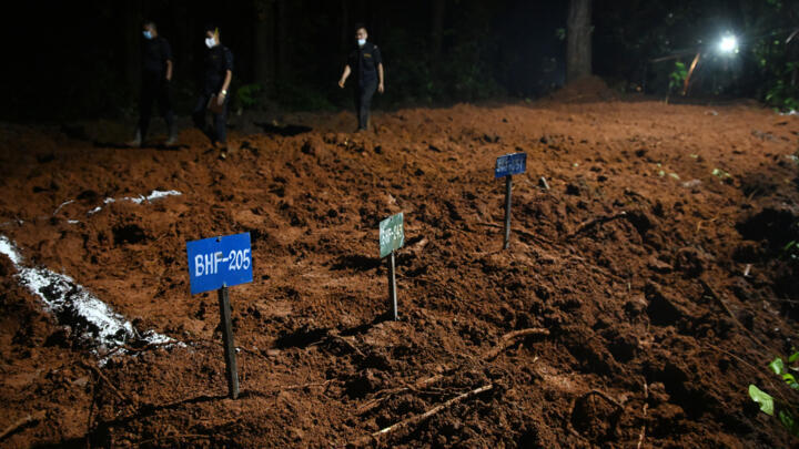 Police walk near the graves of unidentified victims of the Himalayan flood in Devghat, Nepal.