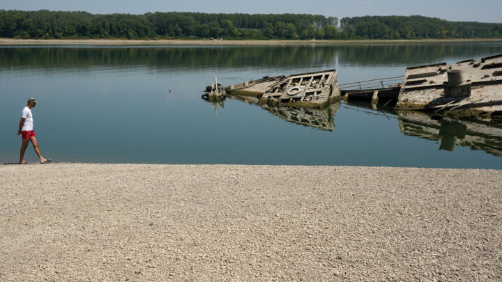 A man walks on the sandbank by the wreckage of a WWII German warship, emerged due to the drought, in front of Djerdap II, a large dam on the Danube River, between Romania and Serbia.