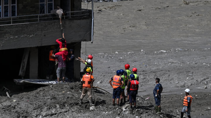 Police personnel rescue stranded residents from houses lying deluged in sludge after flash floods at Trishuli in Nepal's Nuwakot district