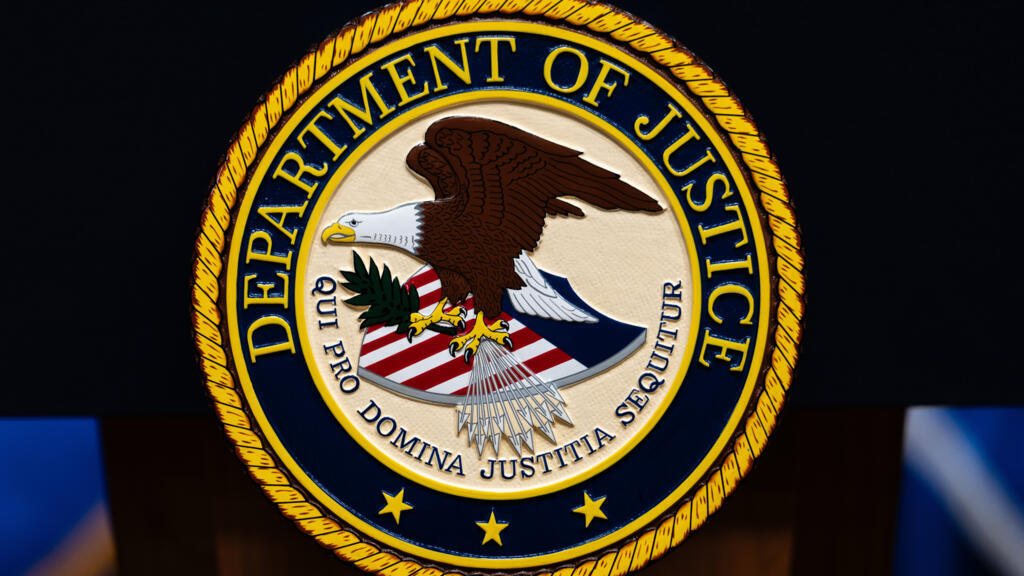The US Department of Justice logo is seen on a podium before a news conference, May 4, 2026, in Washington