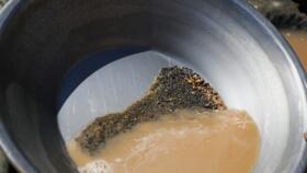 A pan containing gold-bearing sediment and heavy mineral concentrate sits at an artisanal mining site in Sudan, May 8, 2026