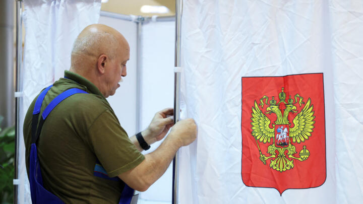 A worker adjusts a curtain in a voting booth at a polling station ahead of the parliamentary elections in Podolsk, Moscow region, Russia, September 17, 2026.
